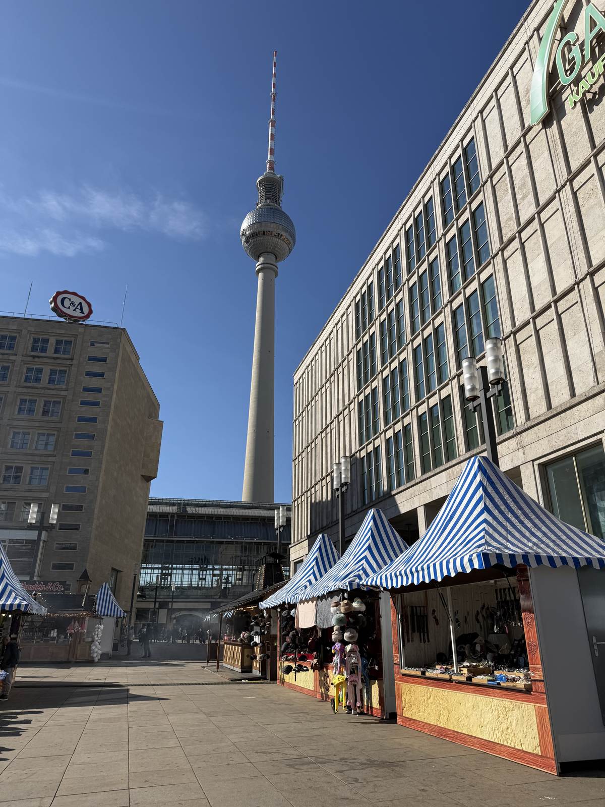 Blue and white striped market stalls on Alexanderplatz with the TV tower behind