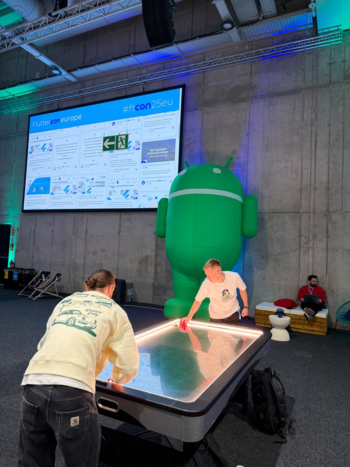 An inflatable green Android next to an air hockey table