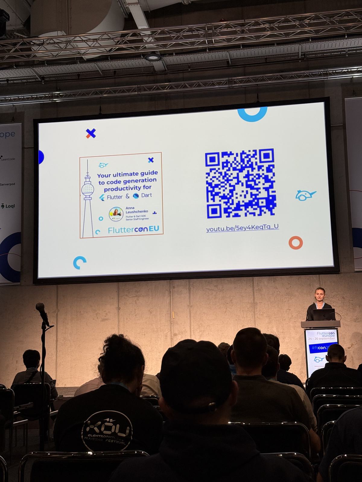 A Fluttercon session room with a QR code on screen