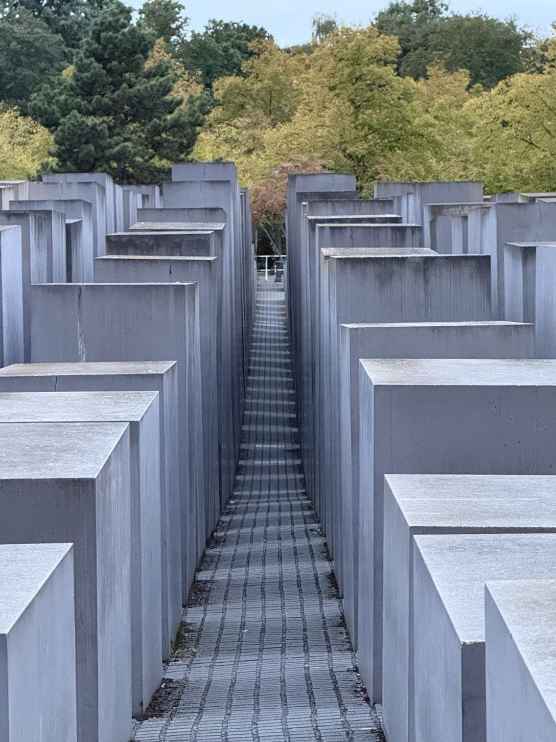 A corridor of the Holocaust Memorial at dusk with trees behind