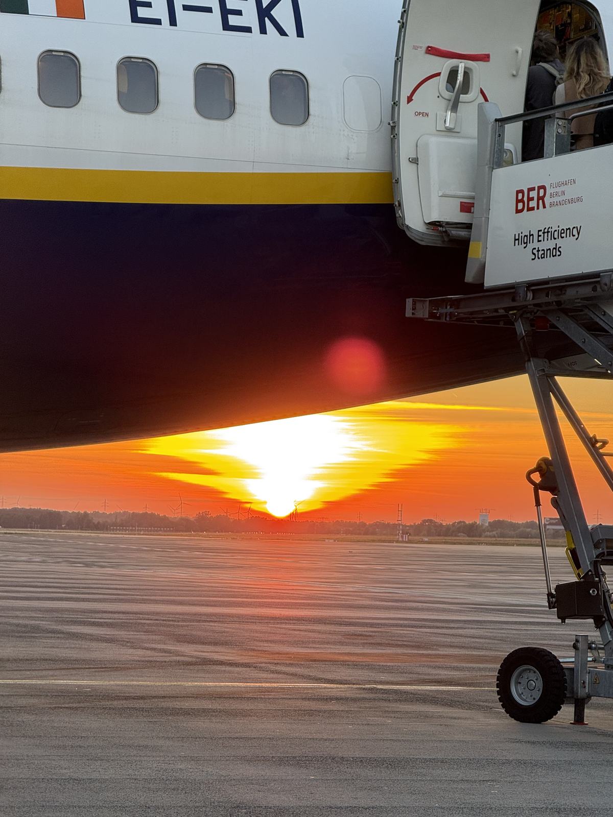 The sun setting seen past the wing of an aircraft