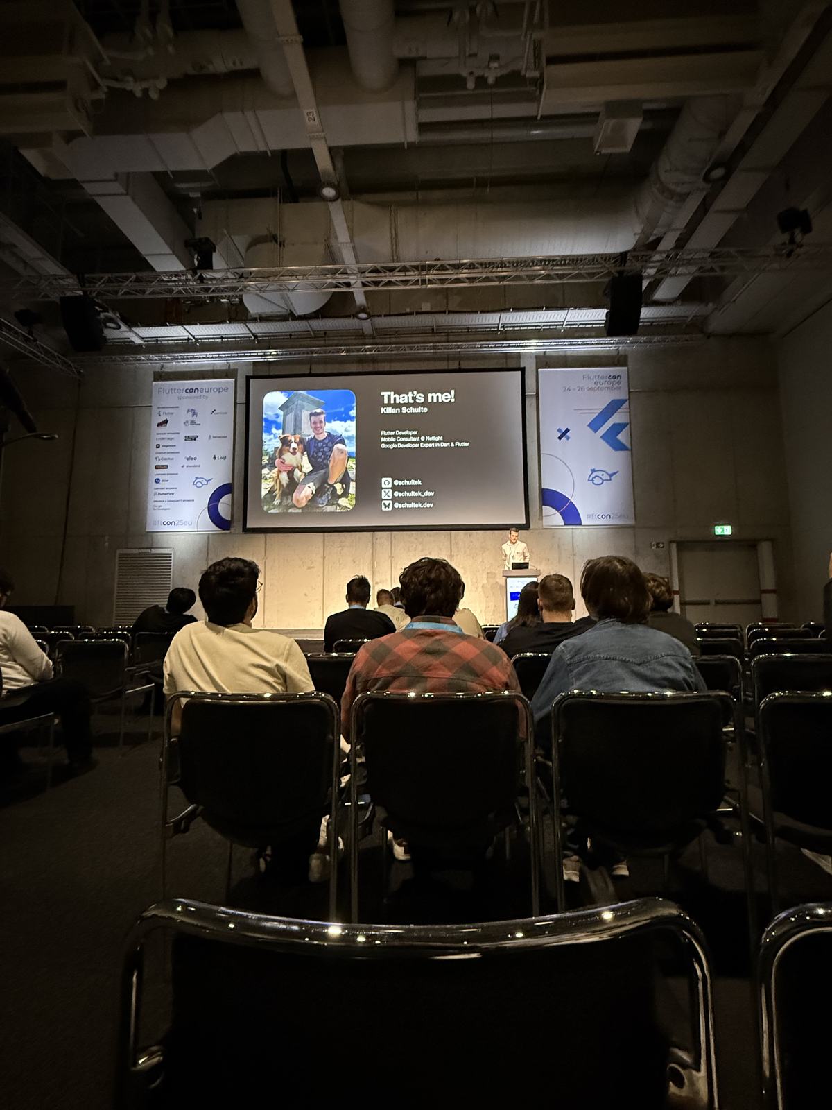 A speaker introducing themselves on the opening slide of a talk