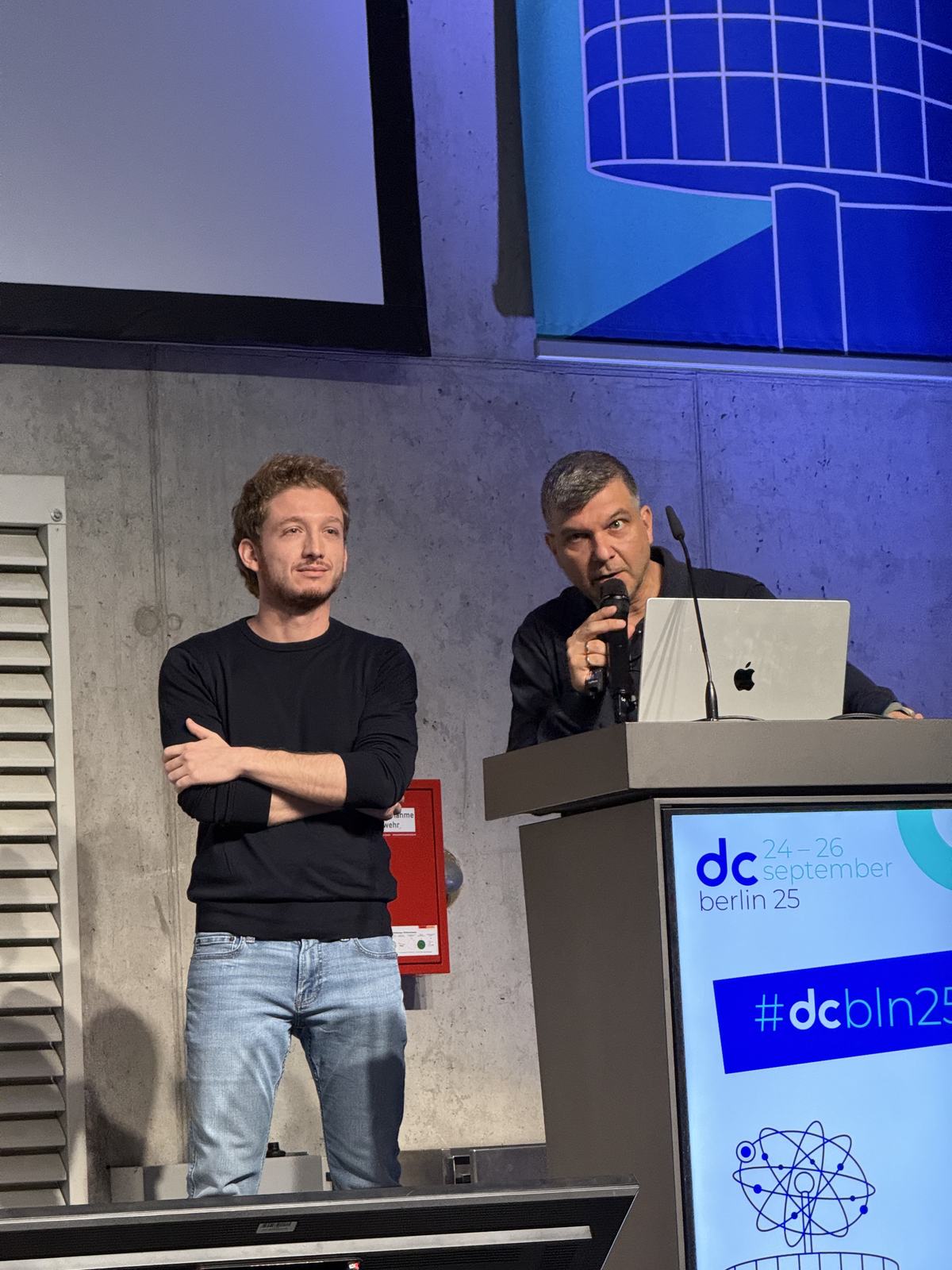 Both speakers standing together at the podium