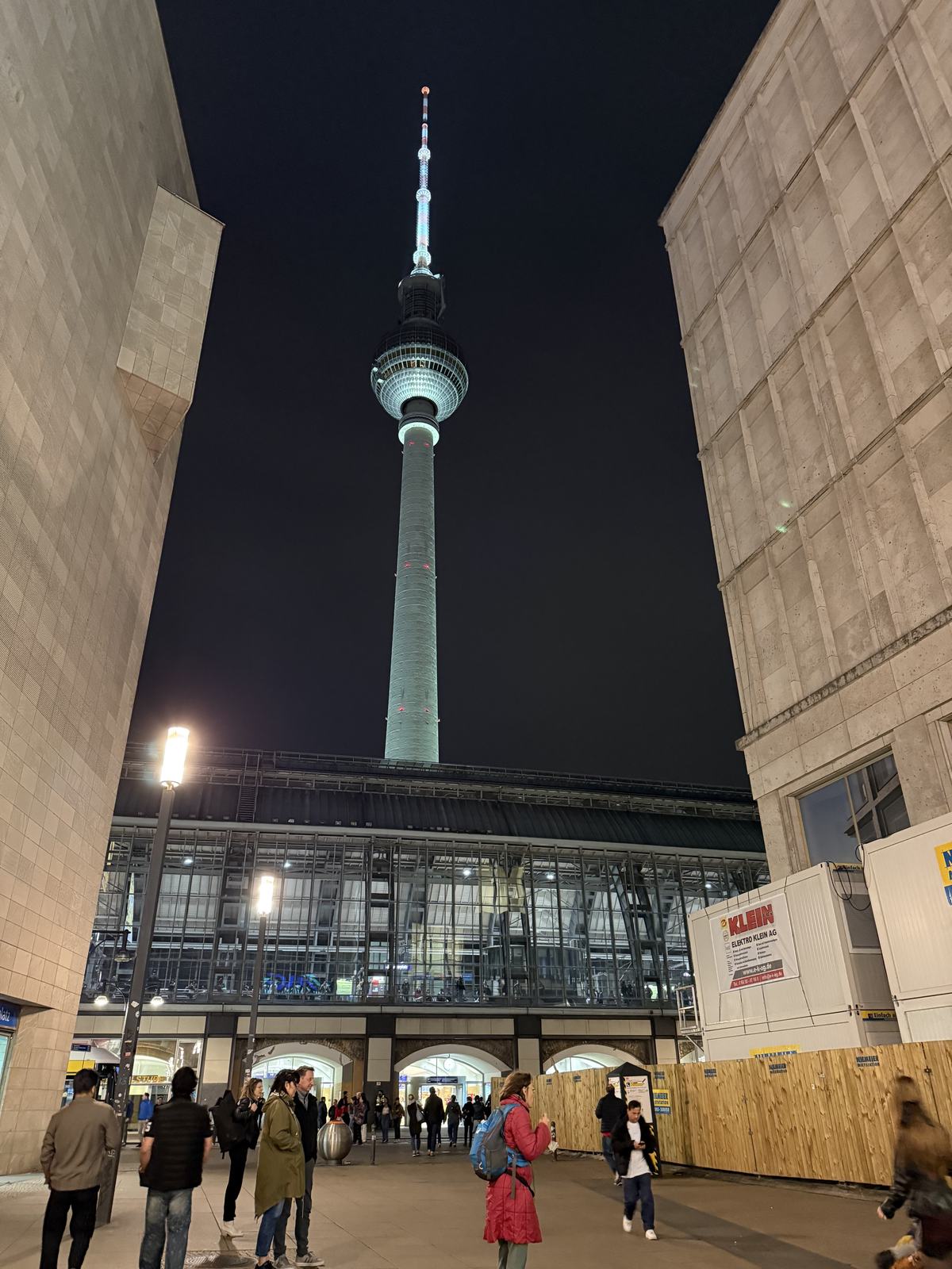 The TV tower lit up at night between two buildings