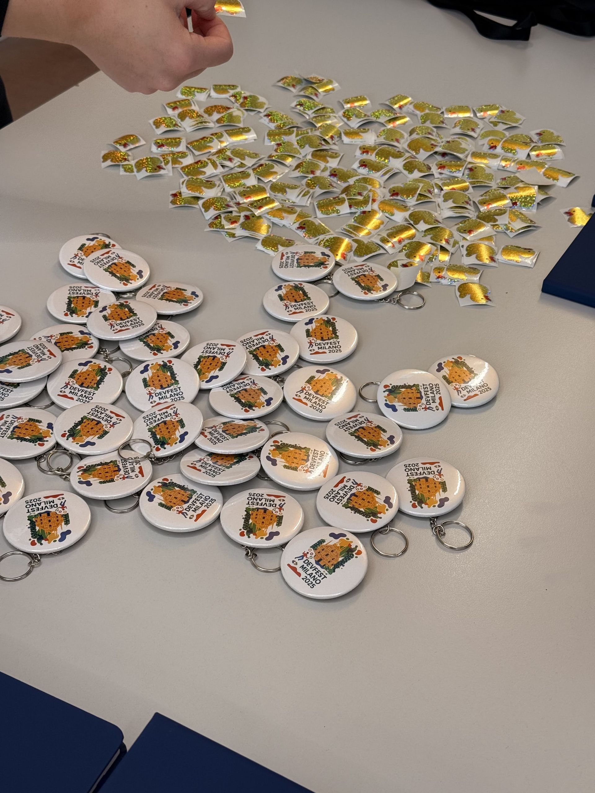 Rows of round DevFest Milano badges laid out on a table