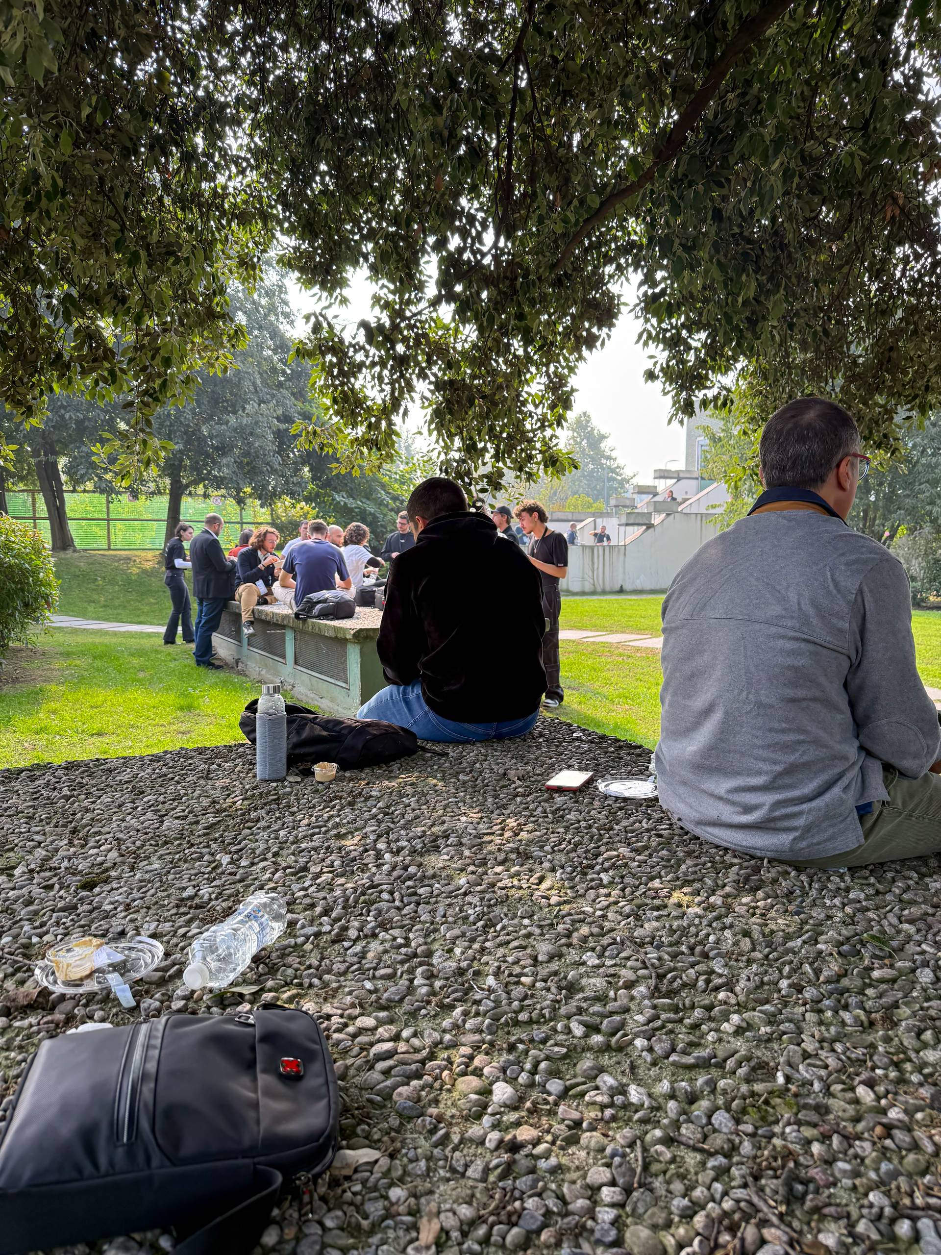 A wider view of the park behind the venue with attendees sitting on the grass