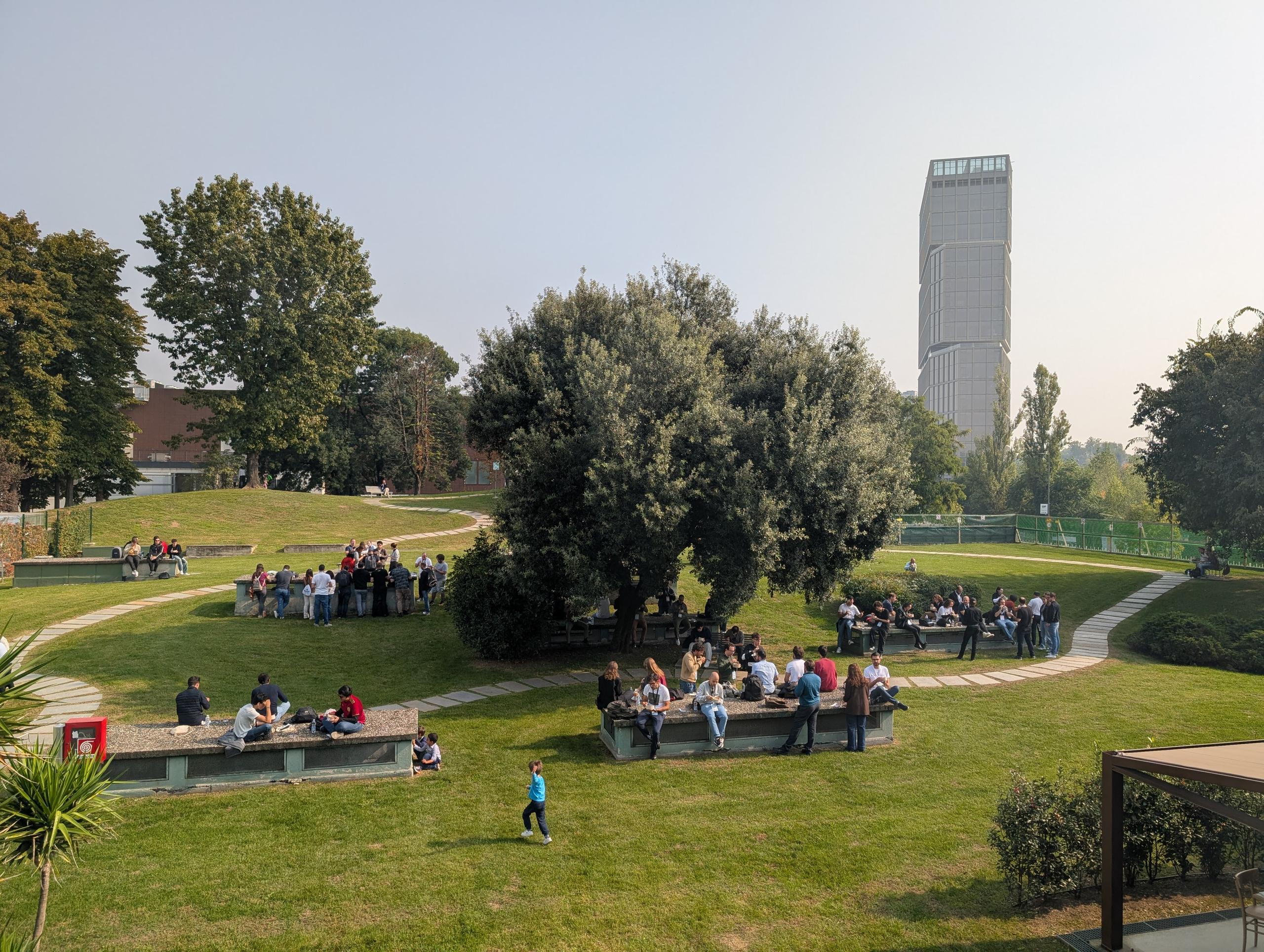 The park with the tower behind it and people sitting at tables