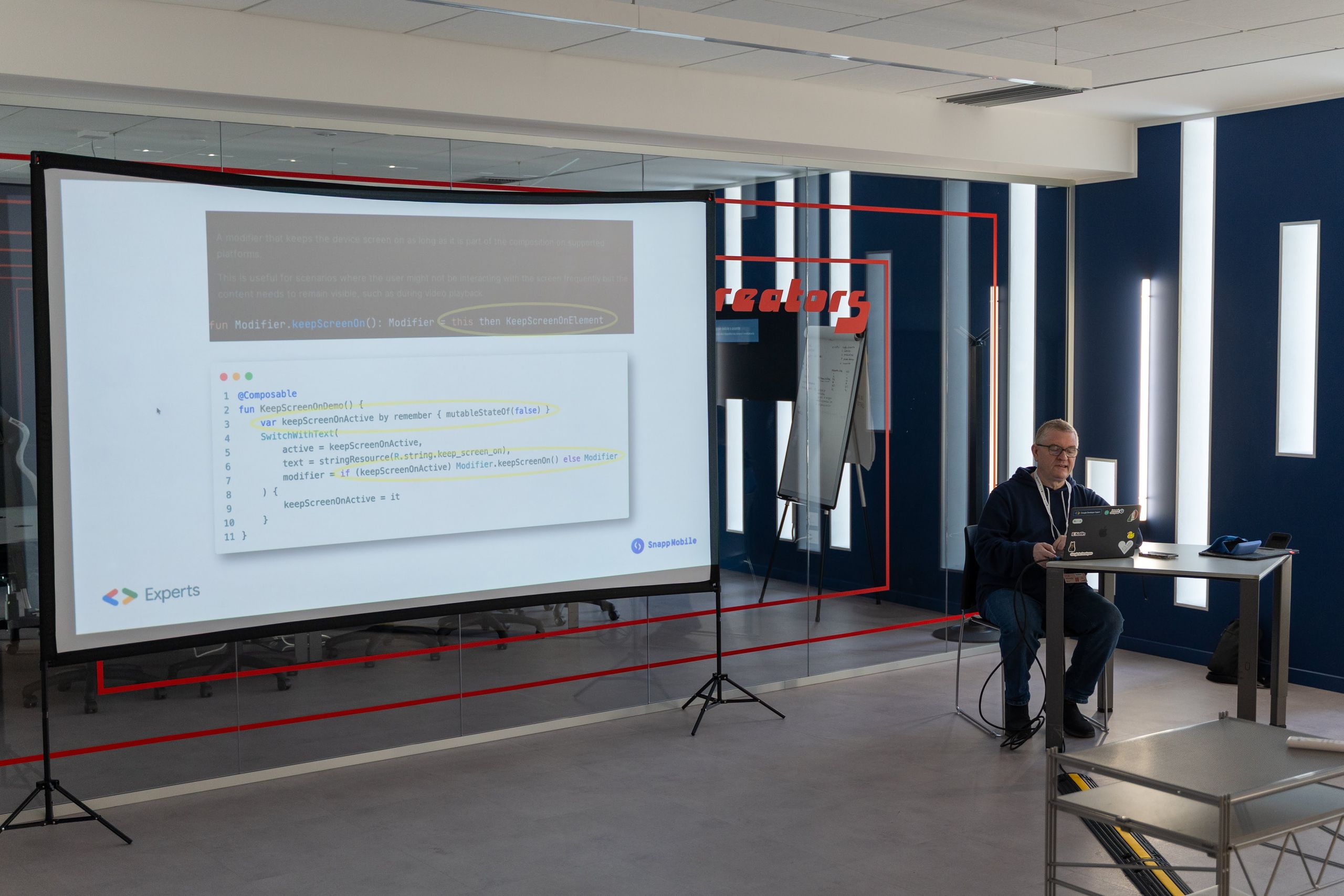 A talk in the big navy room with code on the projection screen