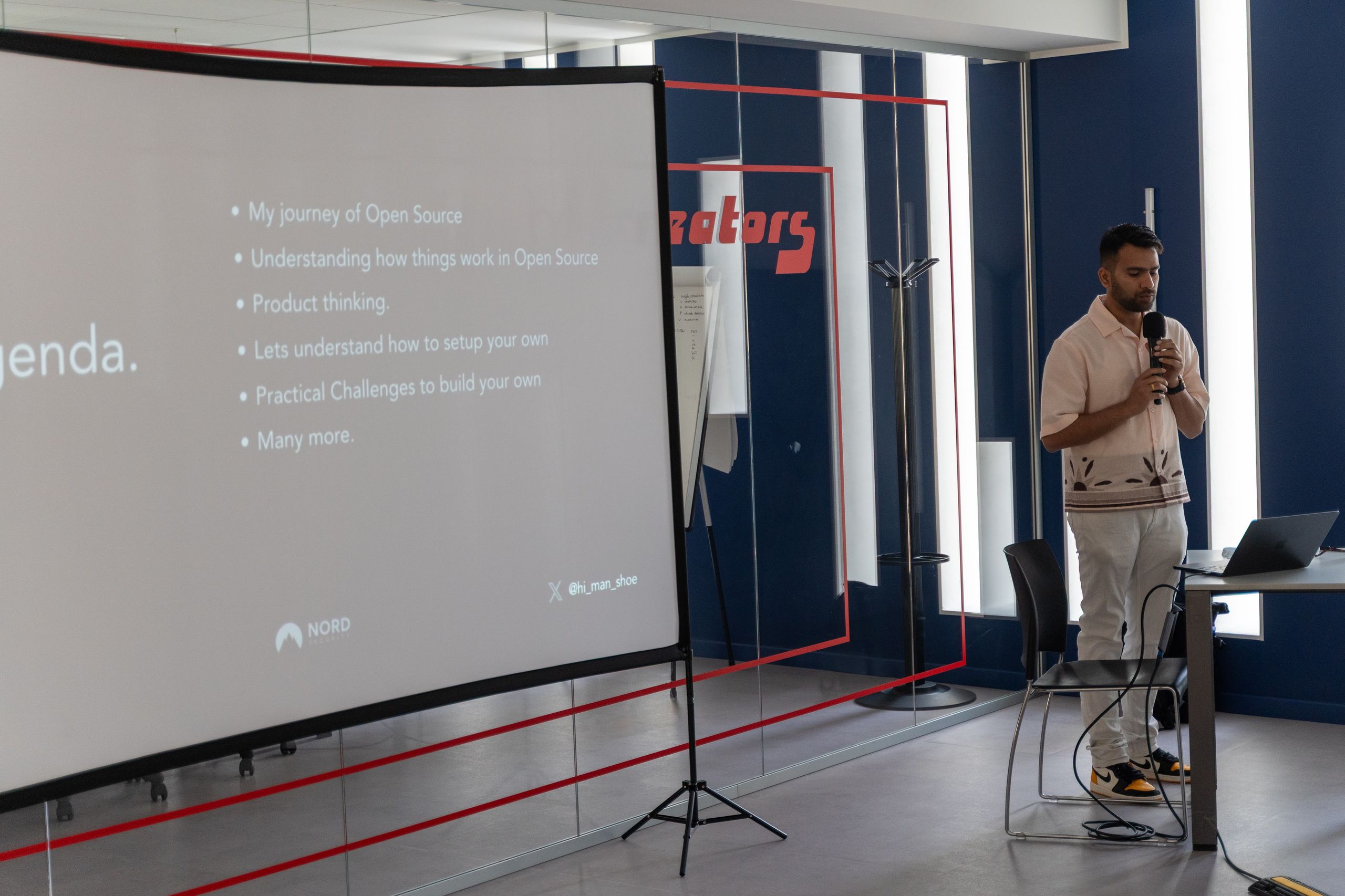 A speaker in front of an agenda slide about open source, with the NORD Security logo