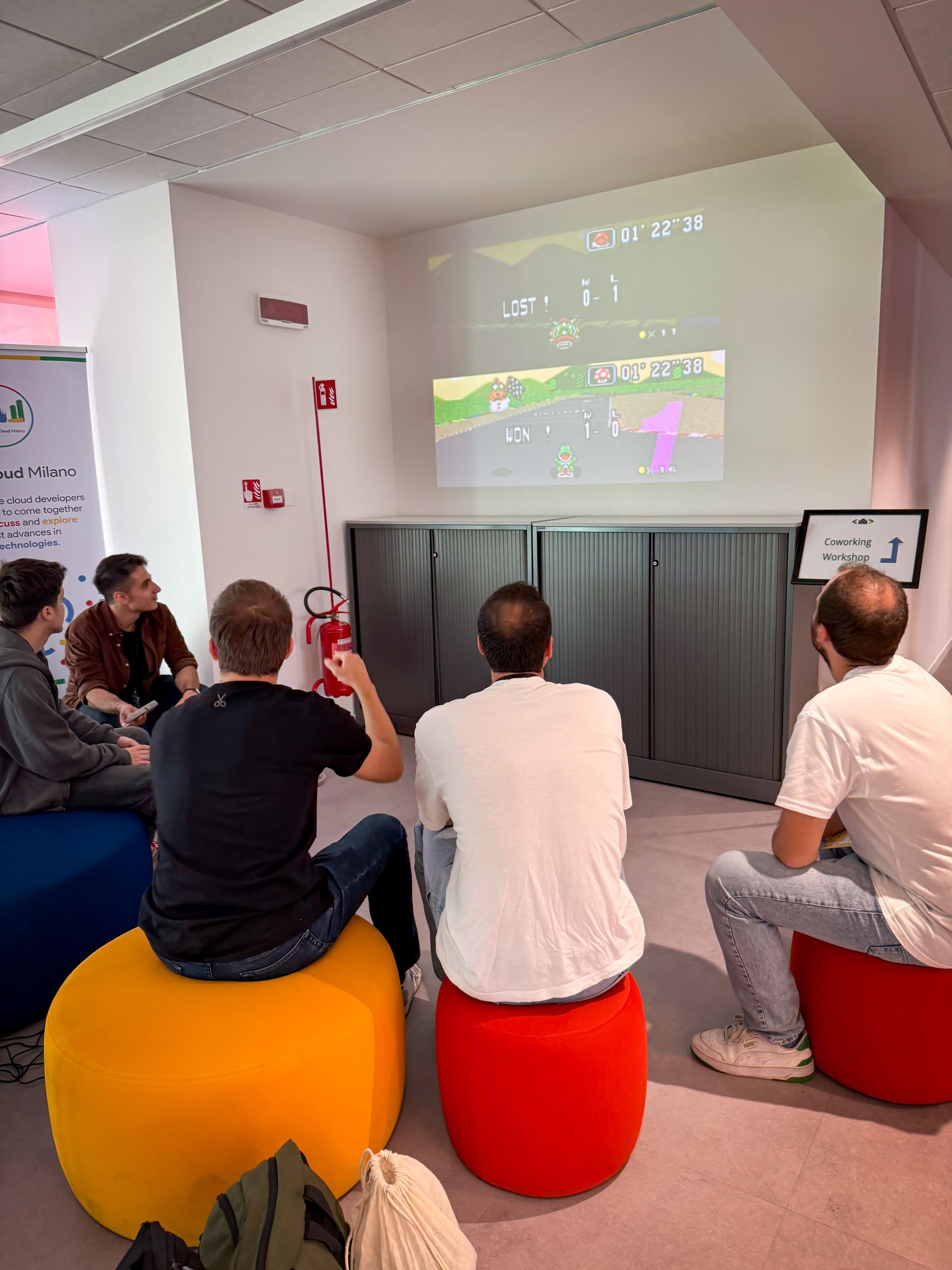 A small room with people sitting on poufs watching a projection during a workshop