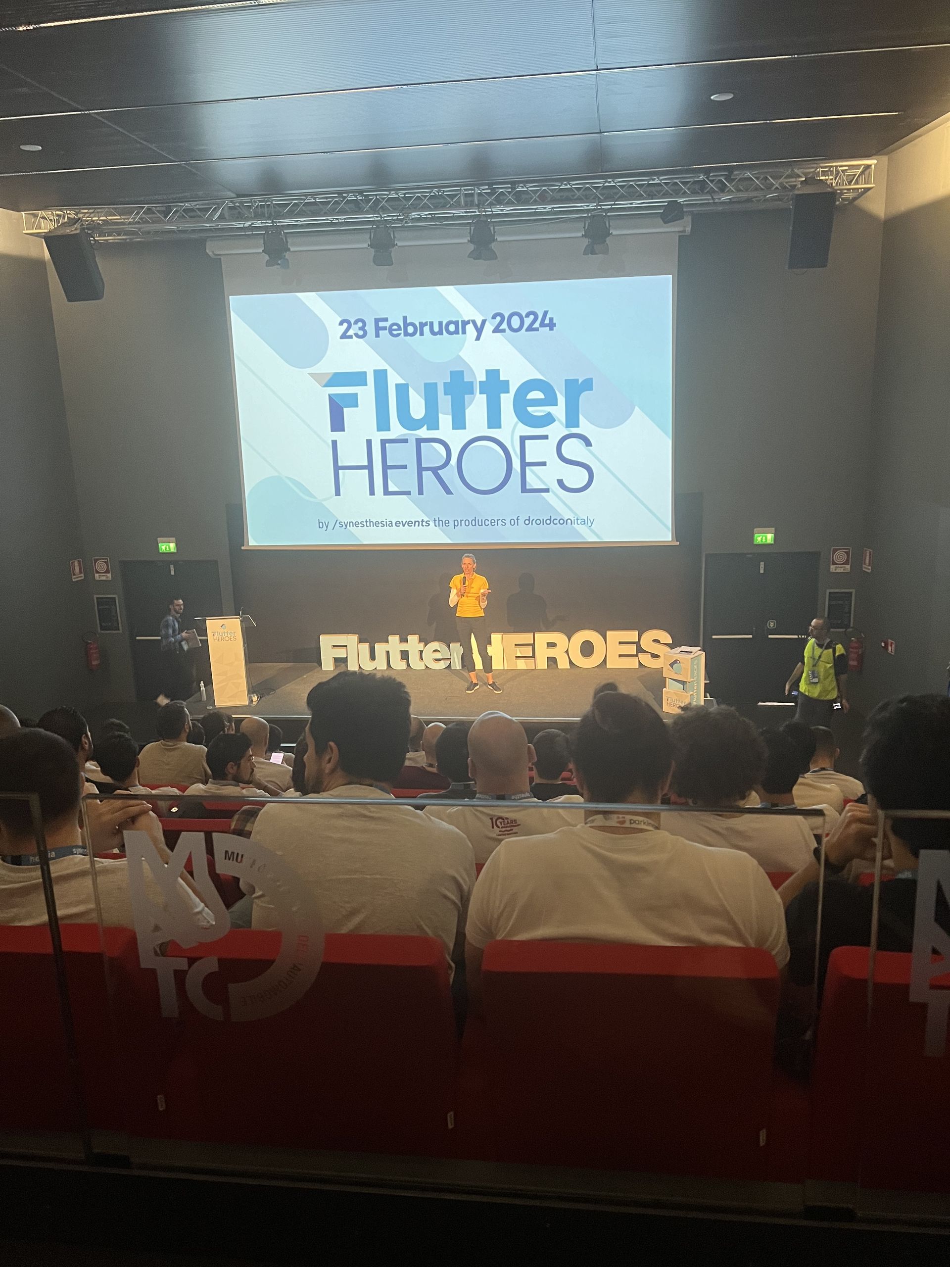 The Flutter Heroes 2024 title slide on the auditorium screen