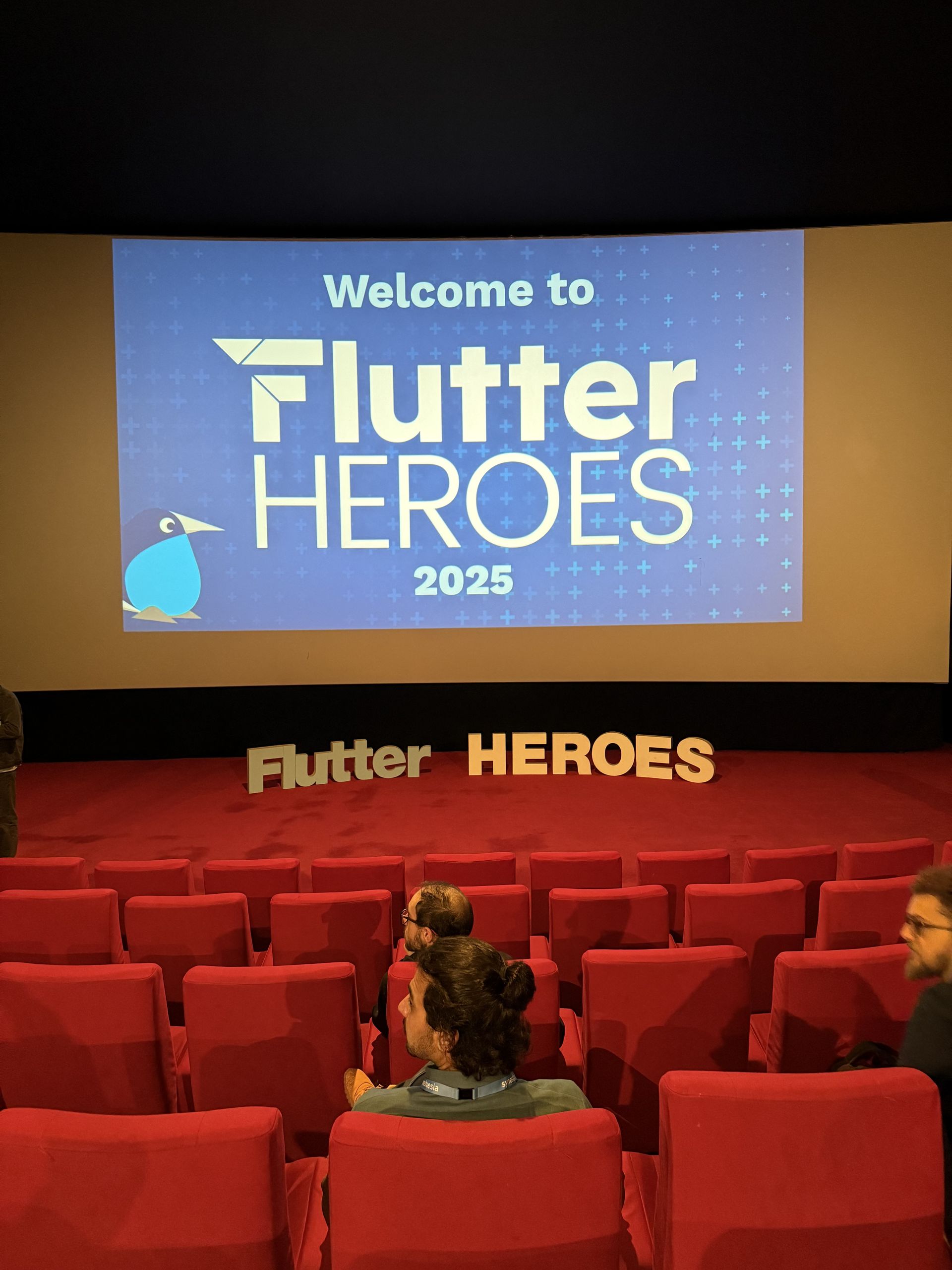 Welcome to Flutter Heroes 2025 on the cinema screen with the letters below it