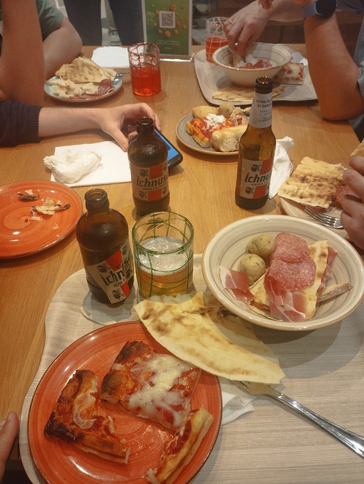 Pizza, prosciutto and beers on the table at the community dinner