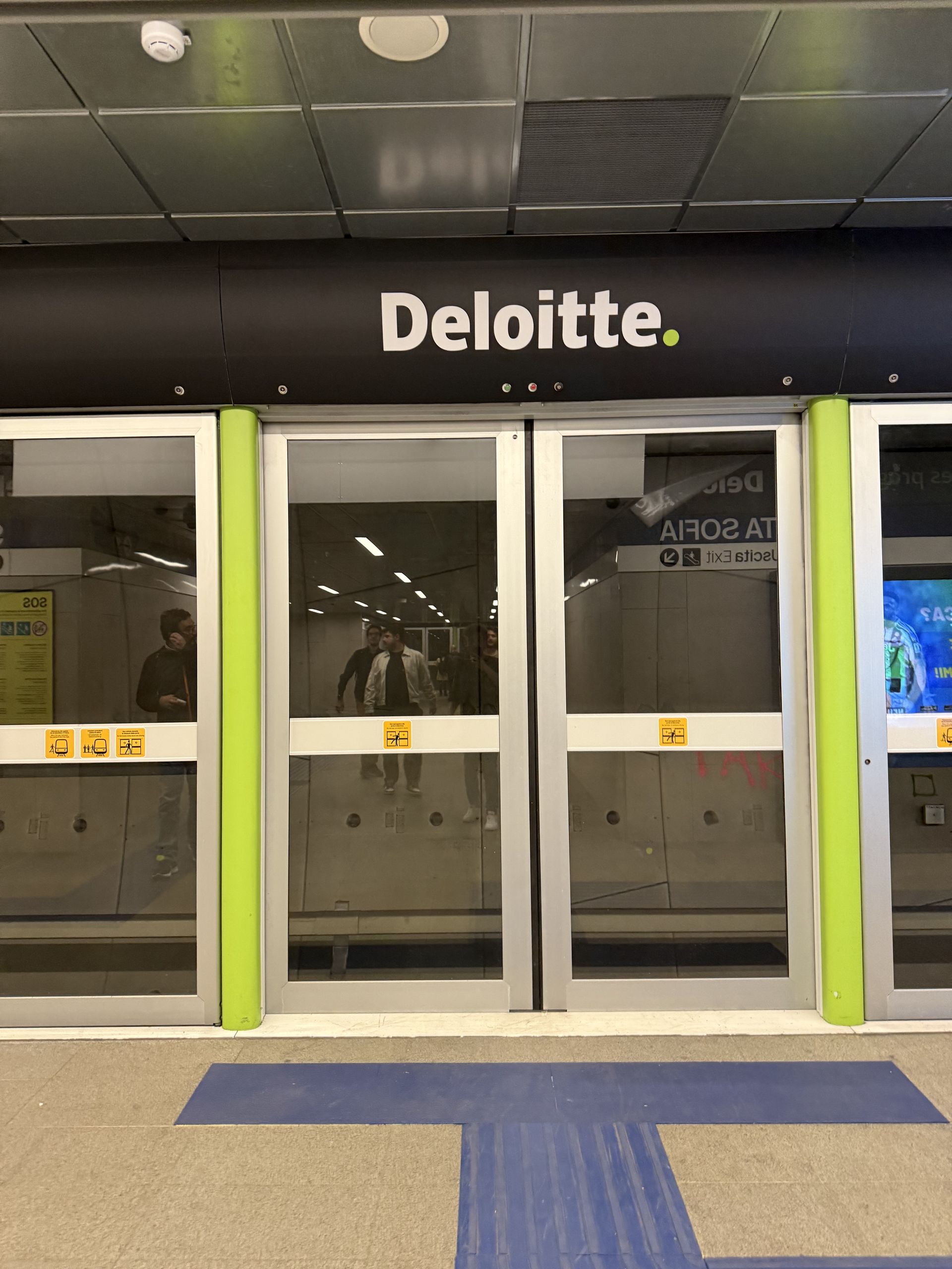 Platform screen doors on the M4 with a Deloitte advert above them