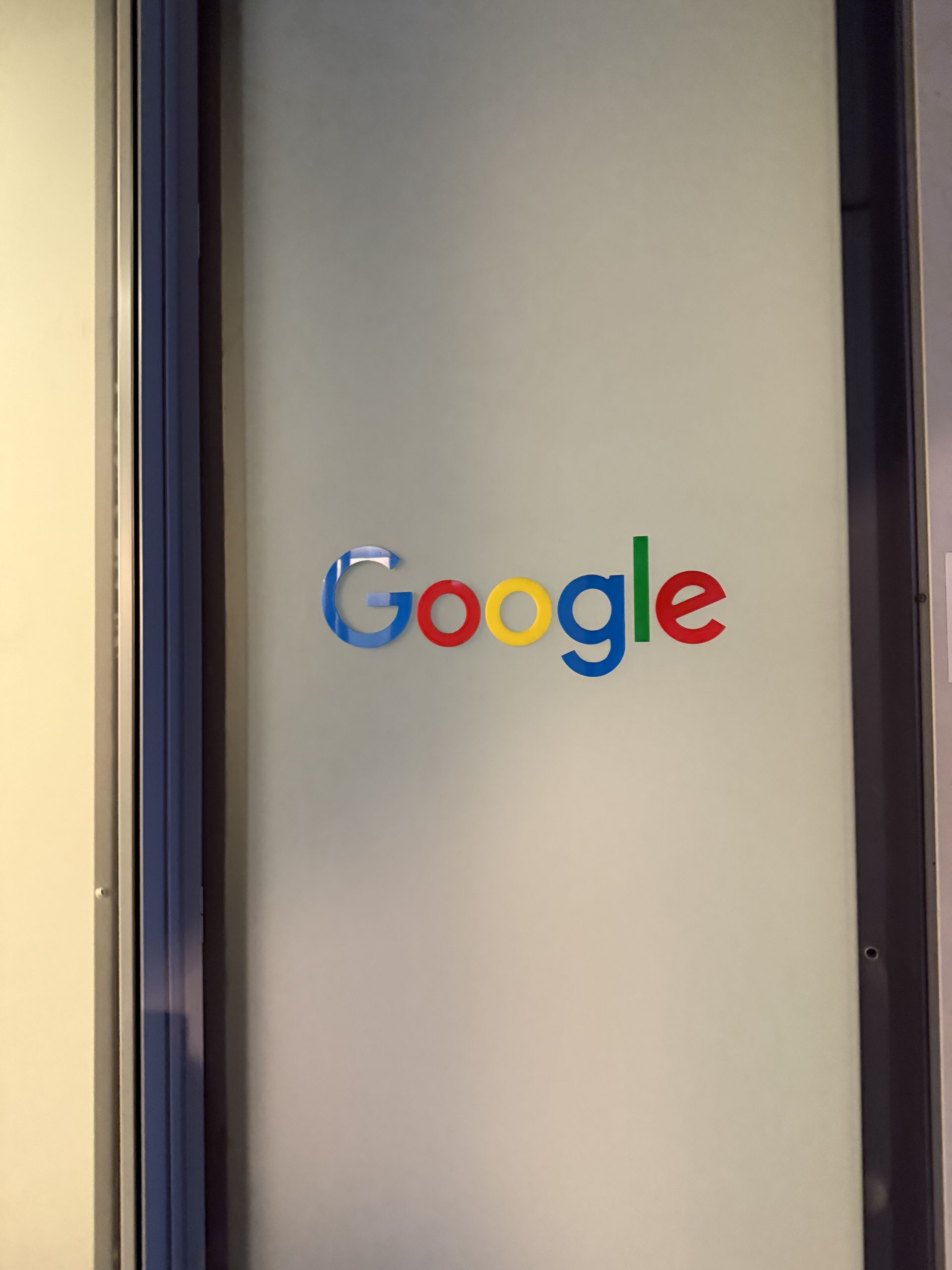 The Google logo on the frosted glass door of the Milano office