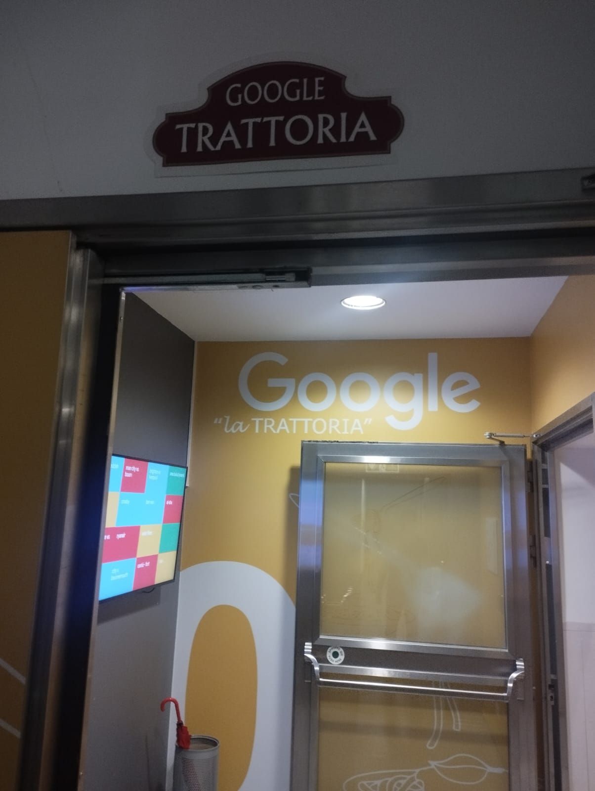 The same brown Google Trattoria sign seen above the canteen door from the corridor