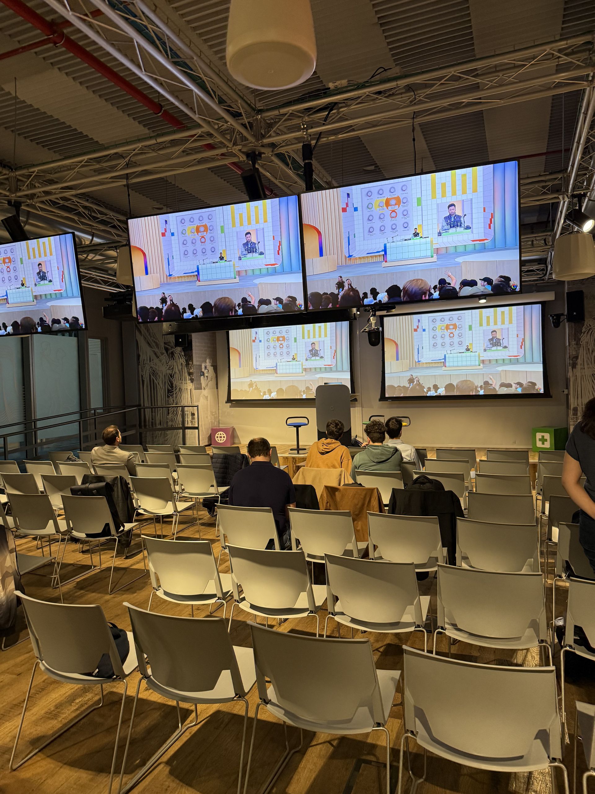The watch party hall with six screens and rows of white chairs