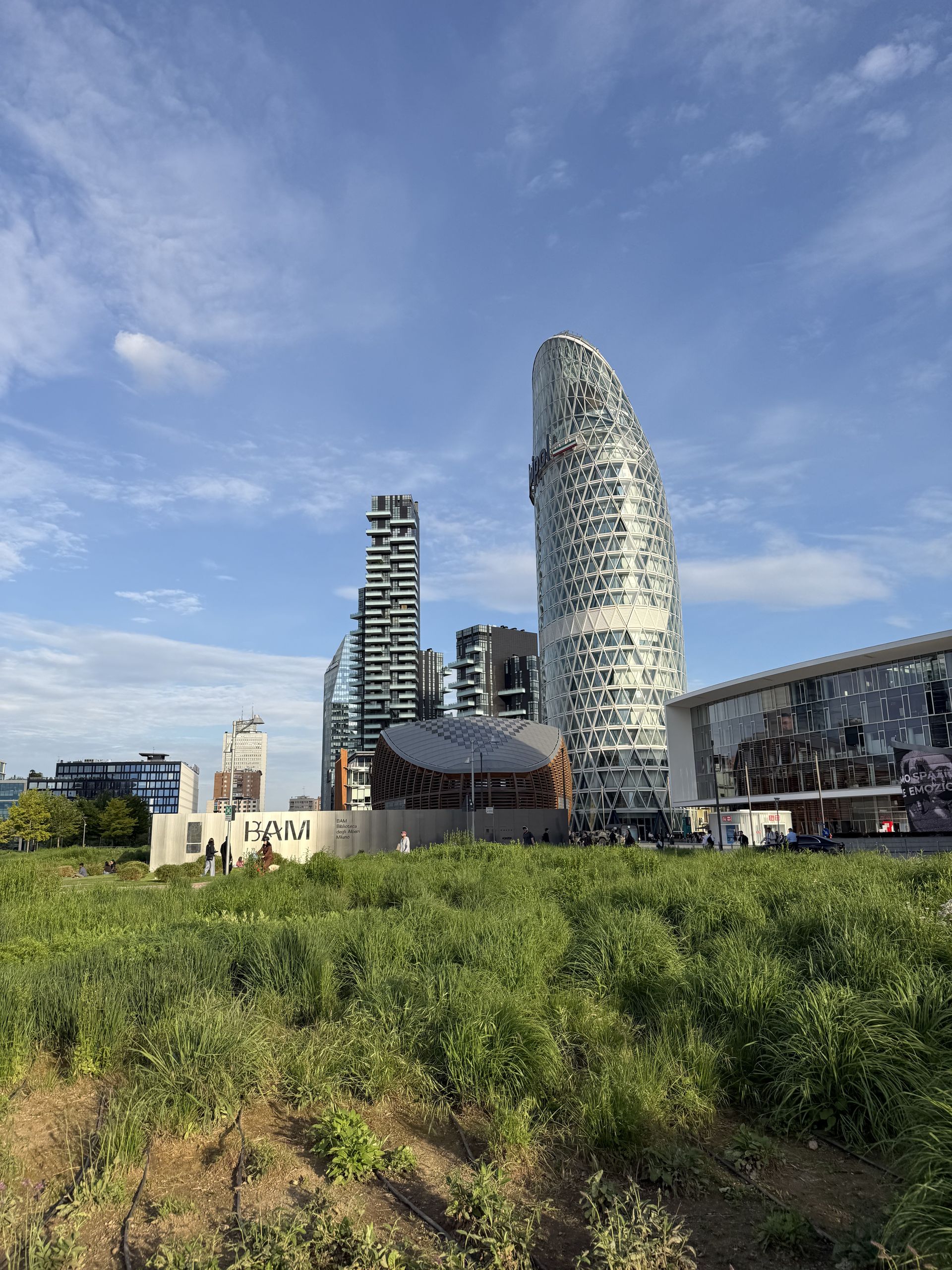 The Unipol Tower curving over the park in the Isola district