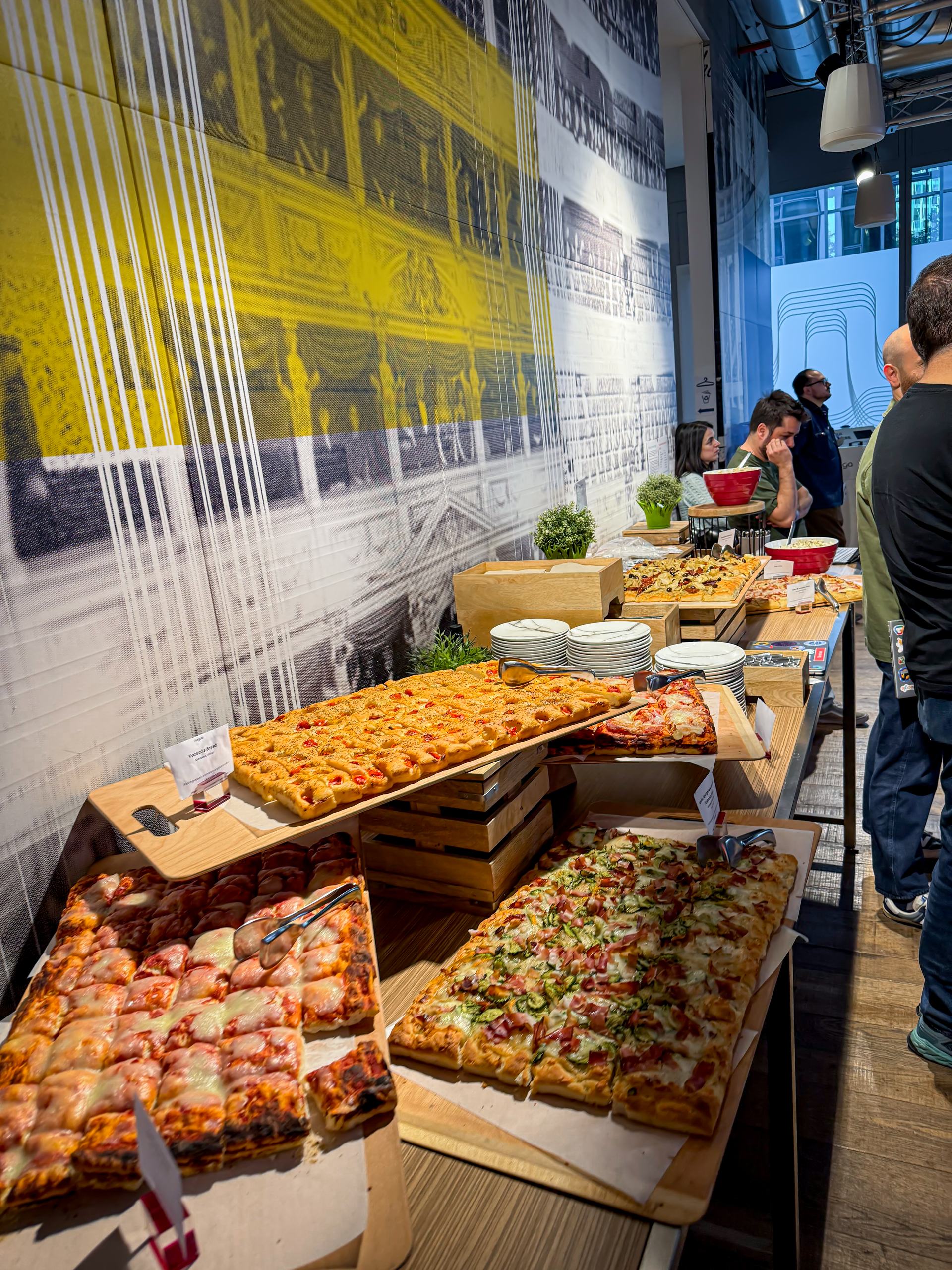 Trays of pizza al taglio on wooden crates against a printed wall