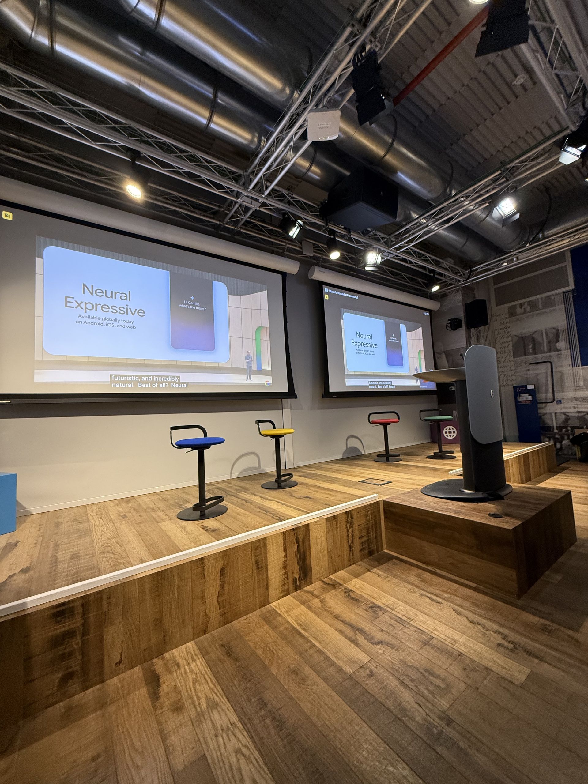 The low stage with two Google-coloured stools and the screens behind