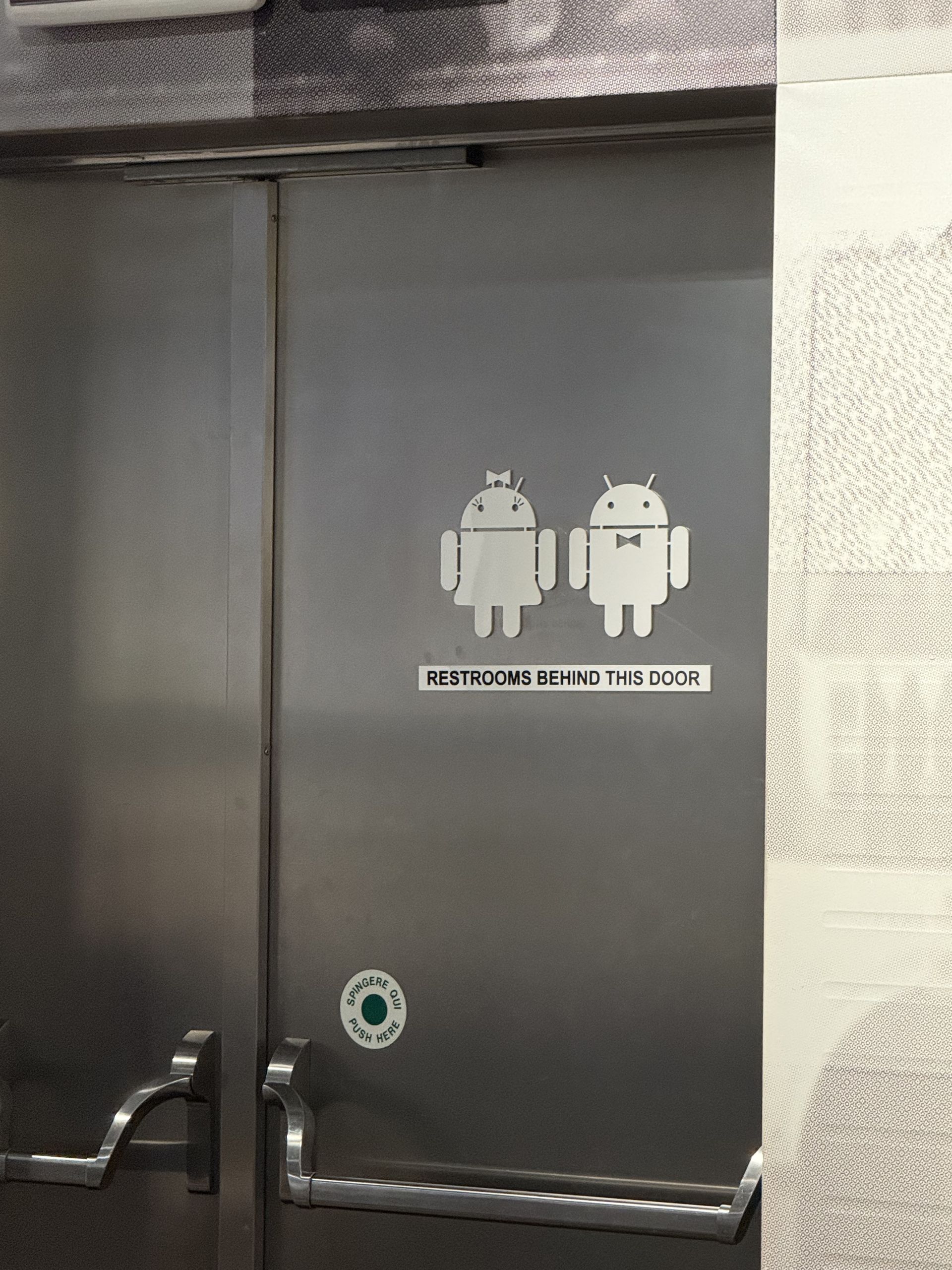 A door signposted Restrooms behind this door with two Android robots on it
