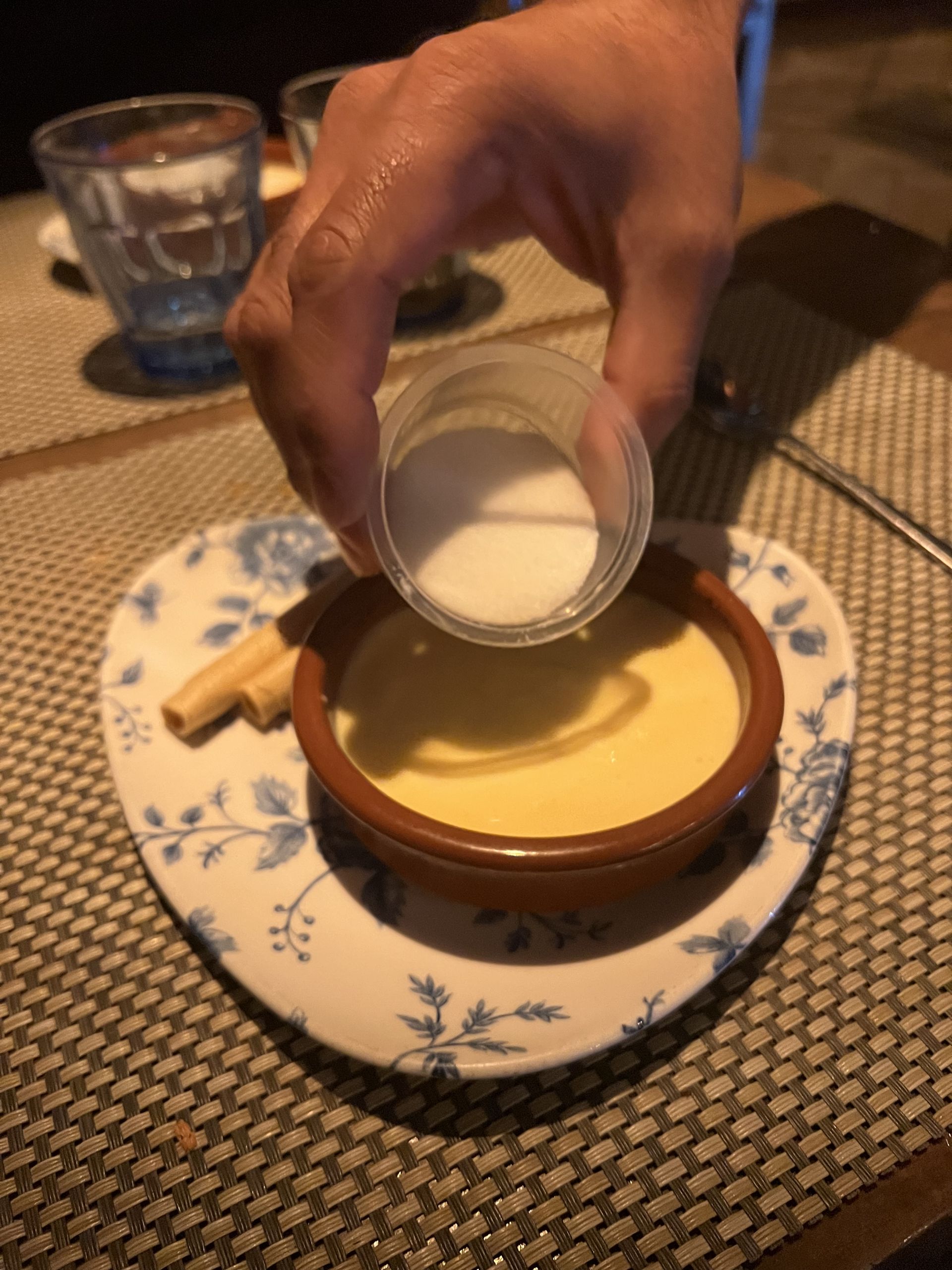 Sugar being poured over a crema catalana before burning it