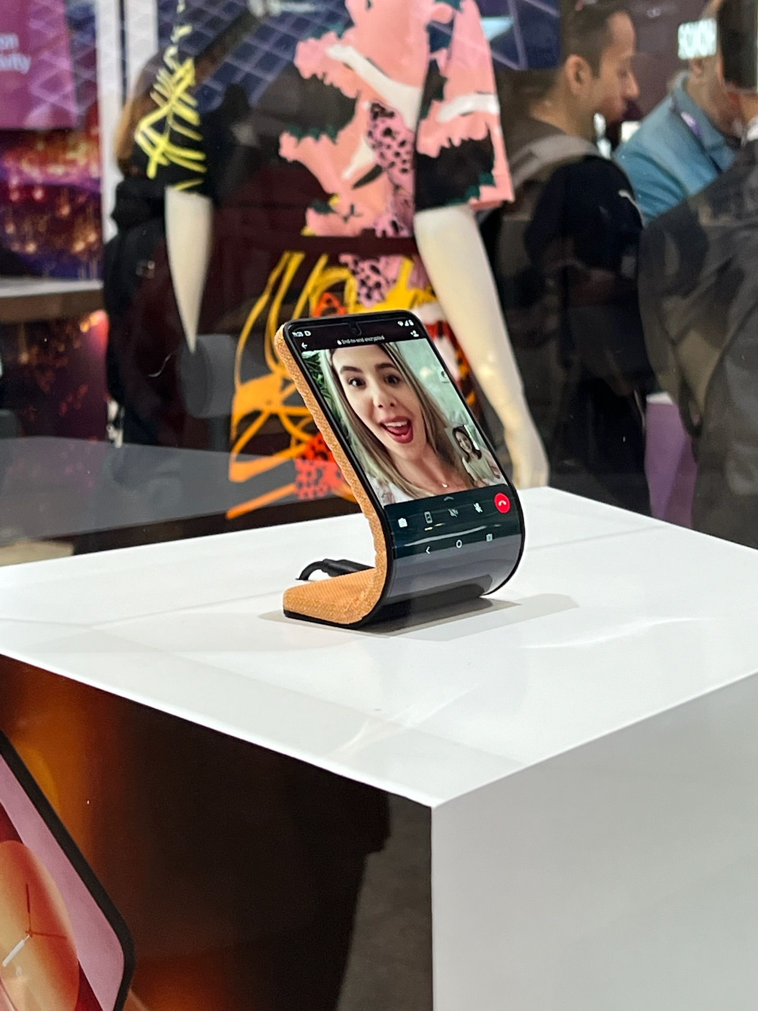 The Motorola bendable concept phone curved into a stand on a pedestal, showing a video call